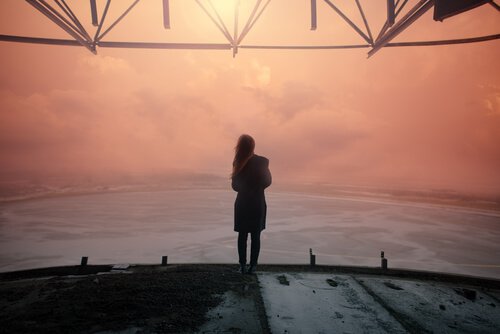 Mulher olhando o horizonte ao entardecer