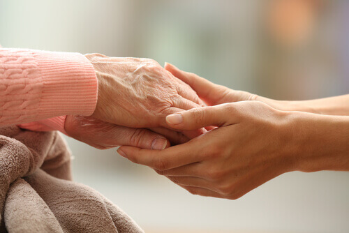 Mulher jovem segurando as mãos de uma pessoa mais velha