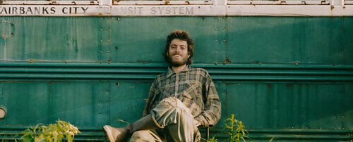 Christopher McCandless sentado apoiado em seu trailer