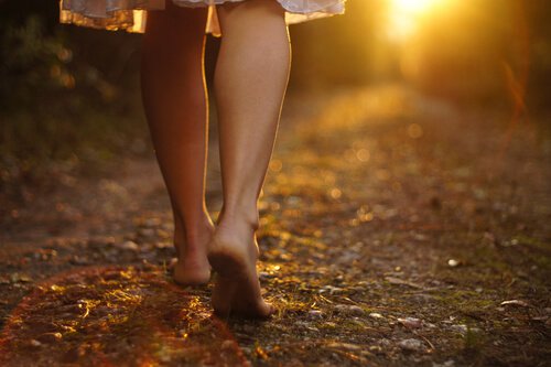 Mulher descalça andando por um caminho