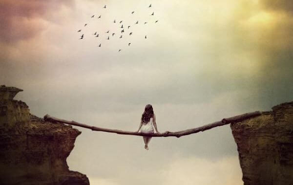 Mulher suspensa em um tronco sobre um abismo