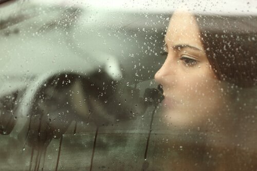 Mulher triste olhando pela janela do carro cheia de gotas