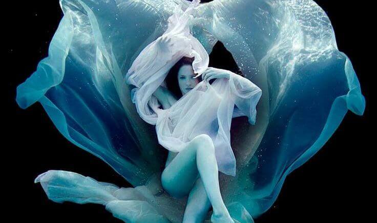 Mulher envolta em véus debaixo d'água