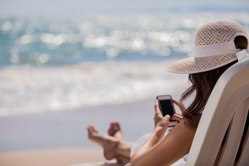 mulher-na-praia-com-o-celular O reflexo da nossa vida nas redes sociais