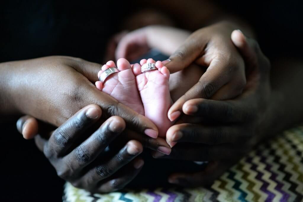 Mãos segurando pés de bebê