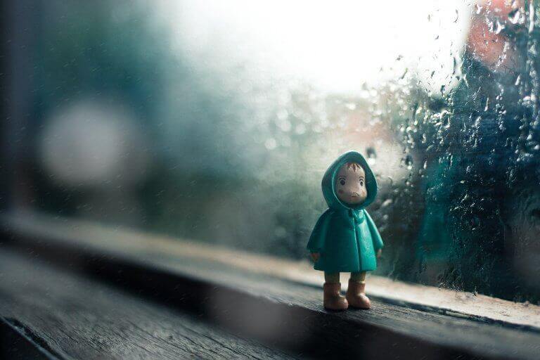 Boneco de criança na janela chuvosa