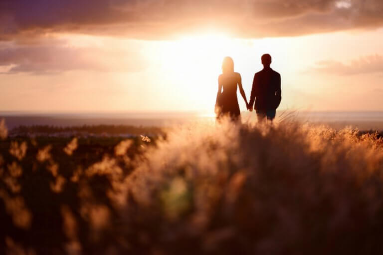 Casal de mãos dadas observando o pôr do sol