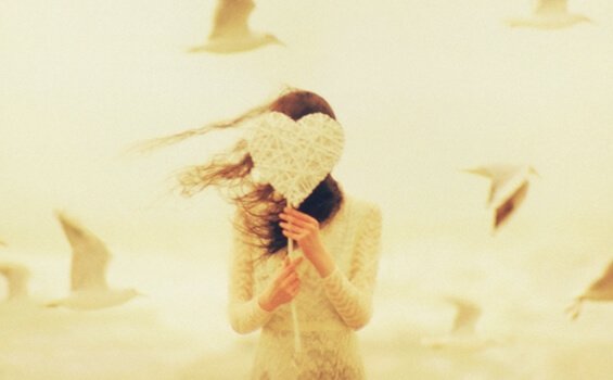 Mulher com coração cobrindo o rosto