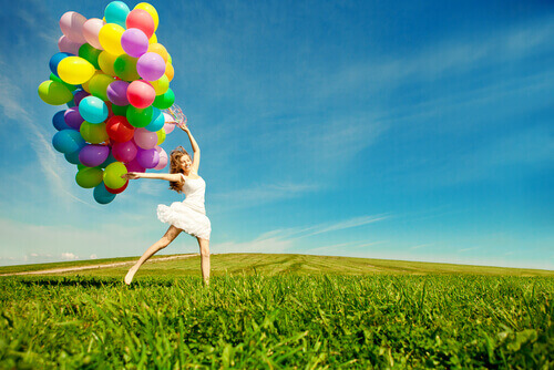 Mulher feliz carregando balões coloridos
