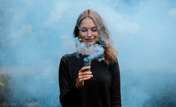 Mulher feliz observando fumaça azul