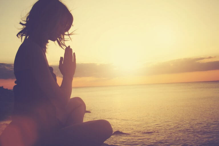 Mulher meditando no por do sol