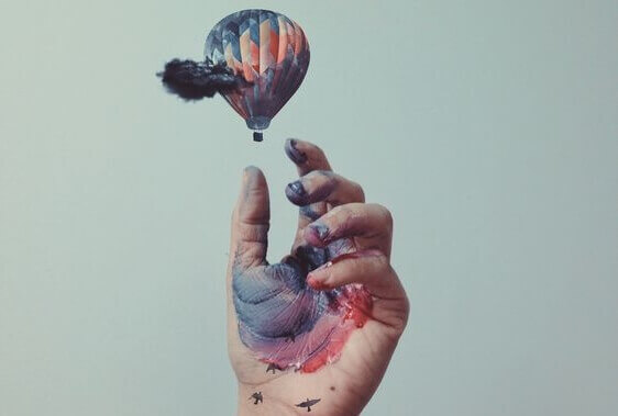 Mão com tinta tentando pegar balão
