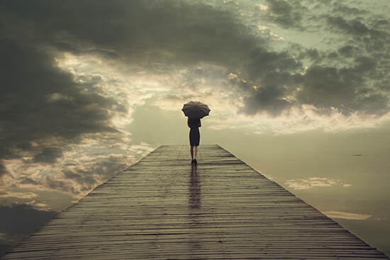 Mulher caminhando em ponte com guarda-chuva