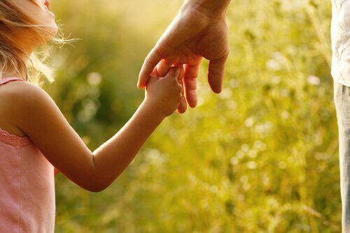 Menina segurando a mão de seu pai