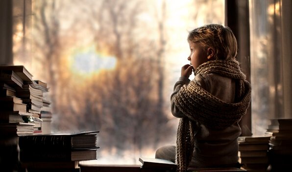 Menino em casa observando livros