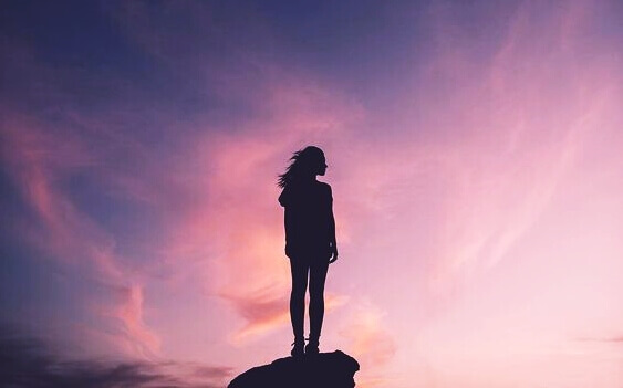 Mulher em cima de pedra desfrutando o por do sol