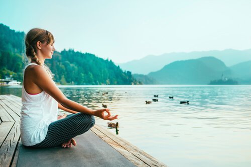 Mulher meditando diante de lago