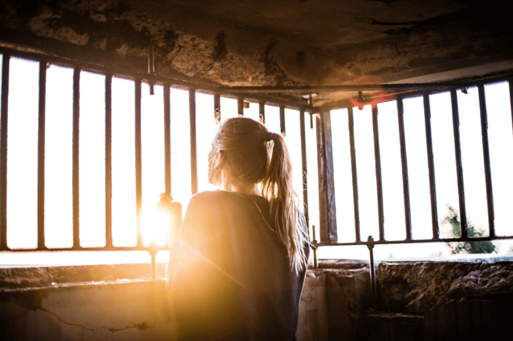 Mulher olhando por janela de grades