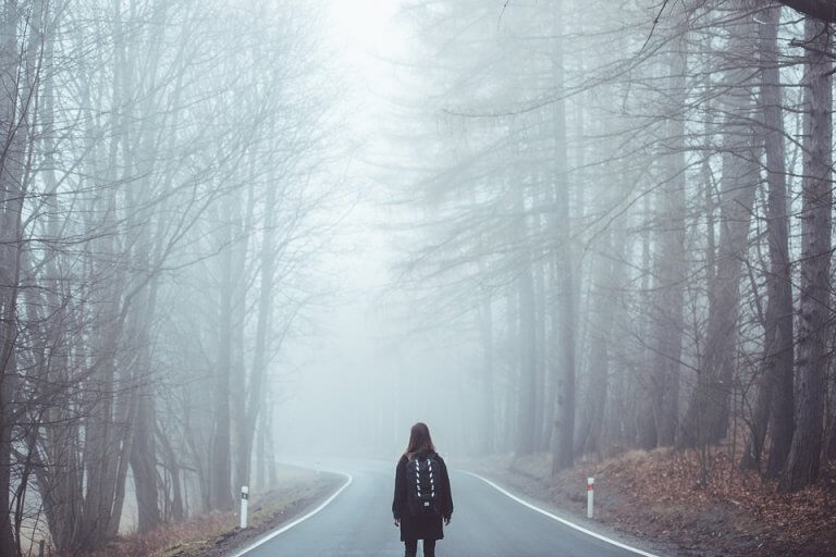 Mulher perdida em estrada com neblina