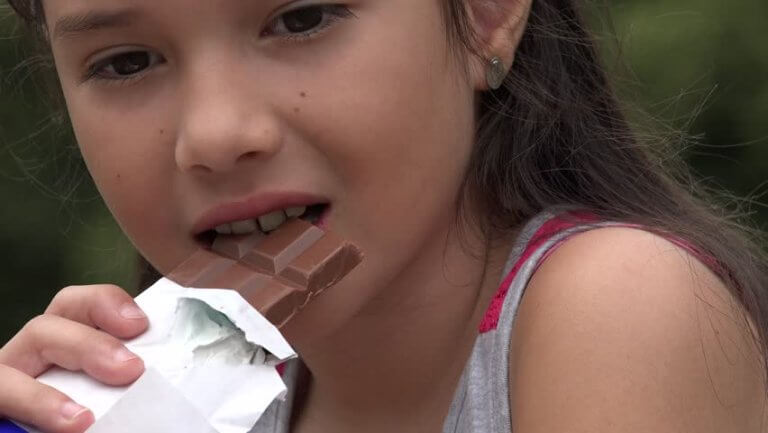 Menina comendo barra de chocolate