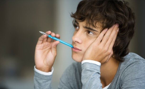 Menino pensando com caneta na cabeça