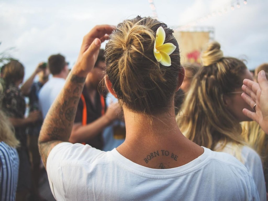 Mulher com tatuagens e flor no cabelo