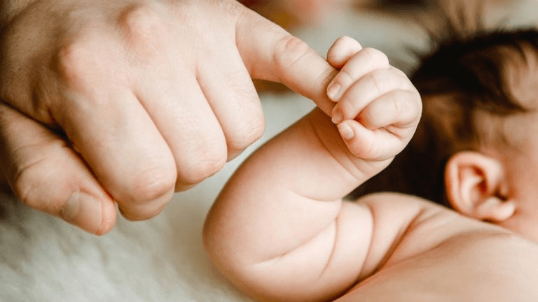 Bebê segurando o dedo do pai