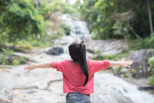 Menina diante de cachoeira