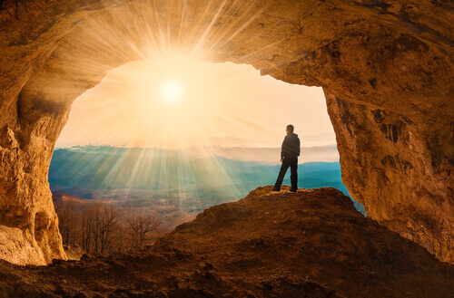Homem em caverna diante do sol