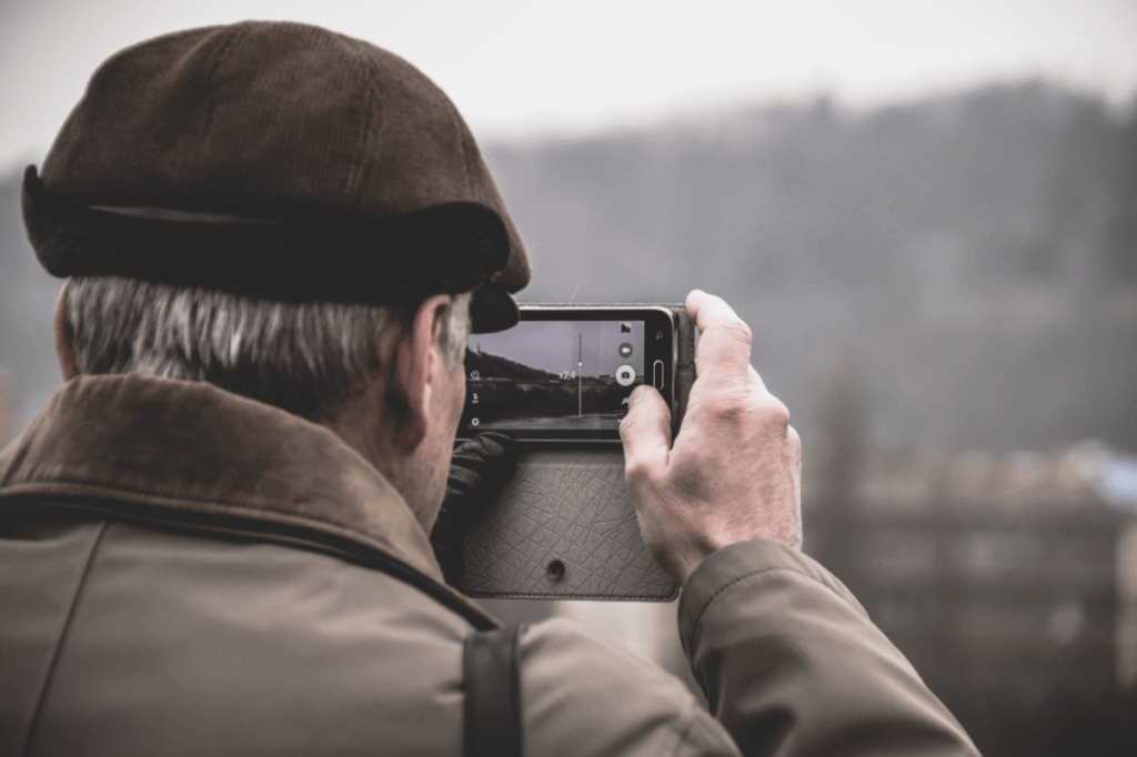 Homem idoso tirando foto com celular