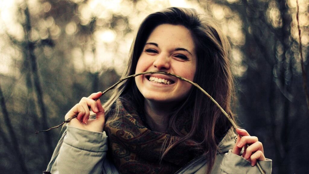 Menina segurando galho no rosto