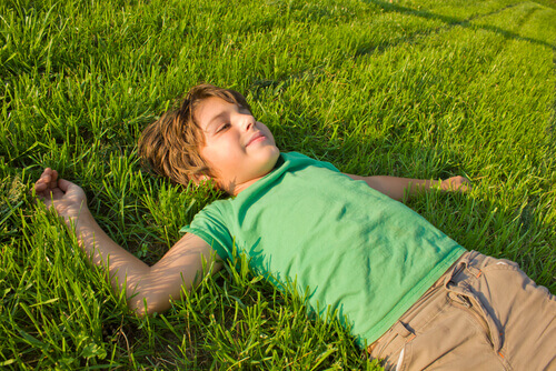 Menino relaxando deitado na grama