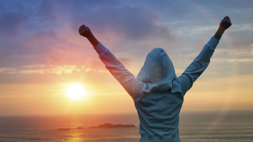 mulher-comemorando-nascer-sol Motivação intrínseca: a possibilidade de fazer algo por si