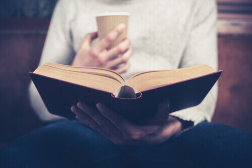 Pessoa tomando café e lendo um livro