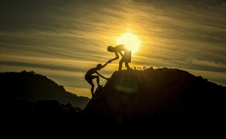 Pessoa ajudando a outra a subir montanha