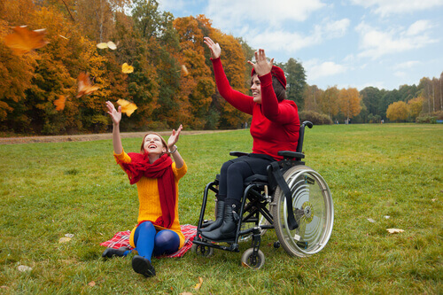 Mulher se divertindo no outono em cadeira de rodas