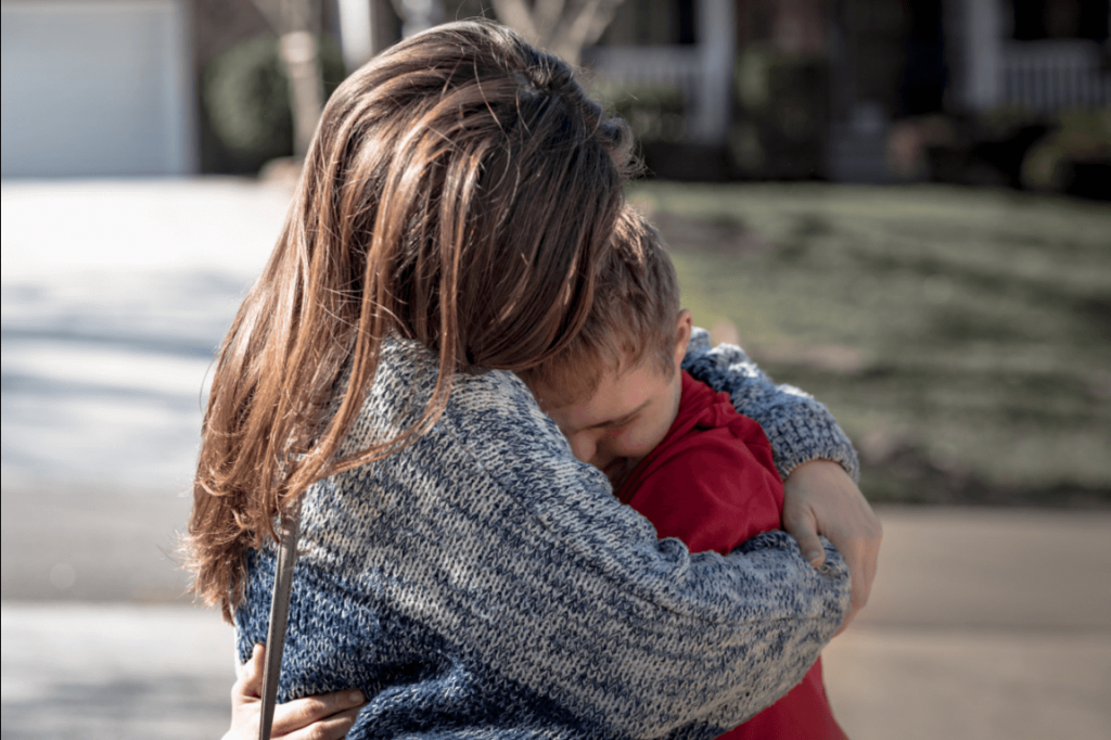 Mãe abraçando filho com deficiência