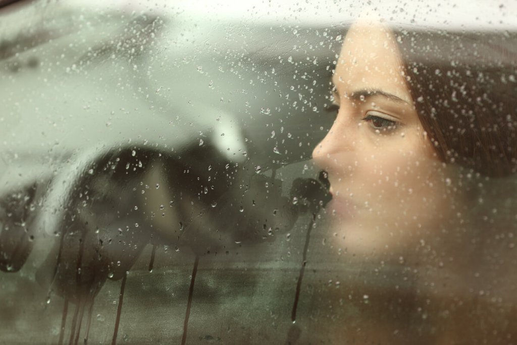 Mulher diante de janela molhada