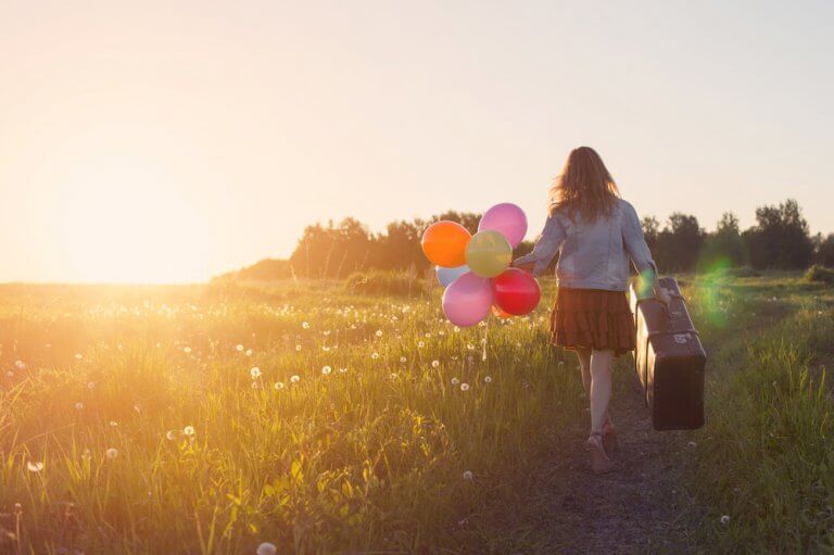 Menina viajando segurando balões coloridos
