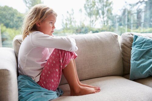 Criança triste sentada em sofá
