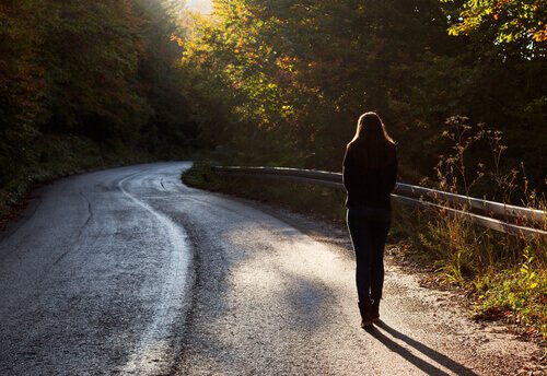 Mulher andando sozinha em estrada