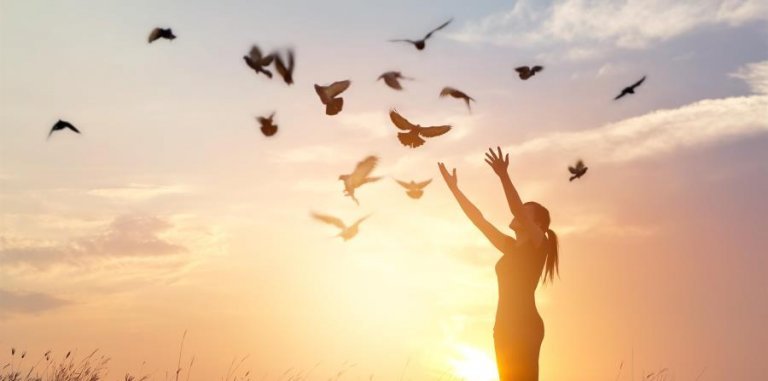 Mulher com pombos voando ao seu redor