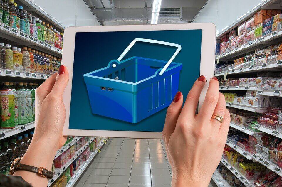 Mulher com tablet com carrinho de supermercado