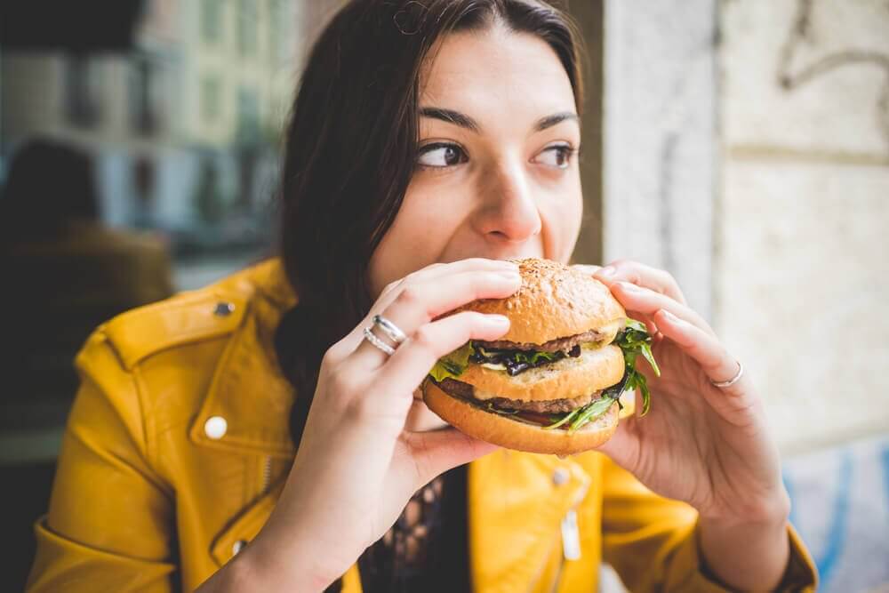 Jovem comendo um hambúrguer