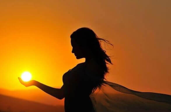 Mulher segurando o sol nas mãos
