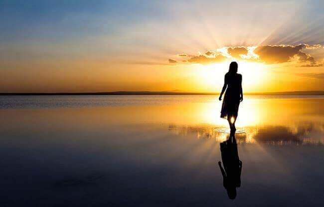 Mulher andando em praia durante o amanhecer