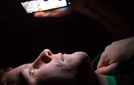 Homem olhando tela do celular deitado