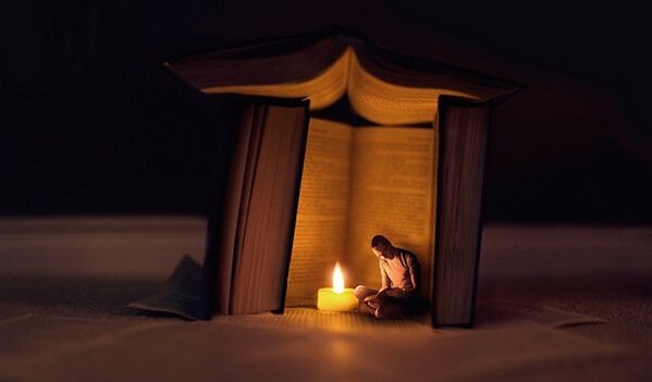 Homem lendo perto de livro gigante