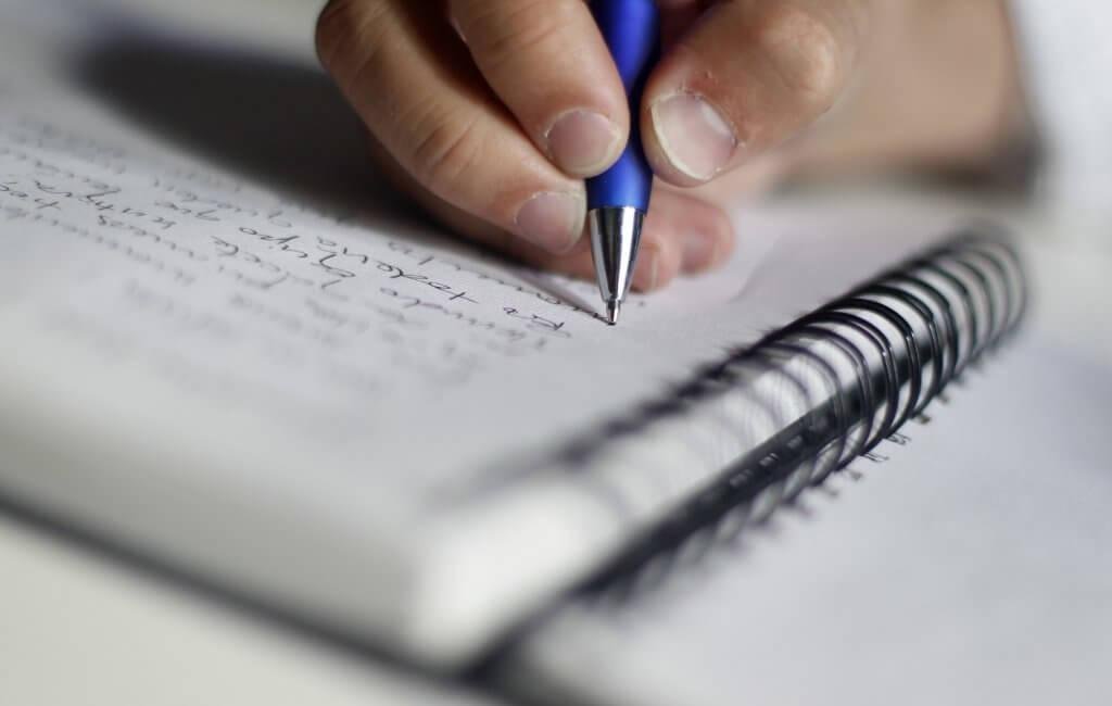 Pessoa escrevendo em caderno