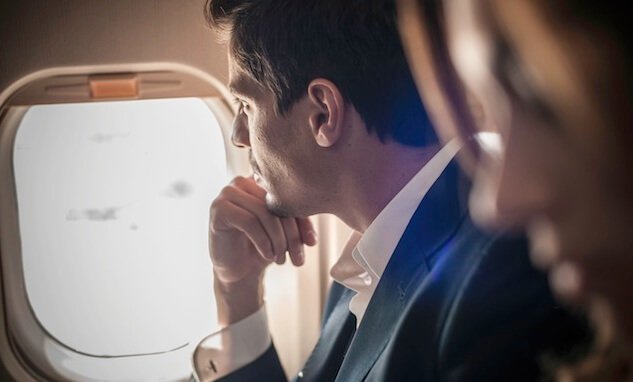 Homem olhando pela janela do avião